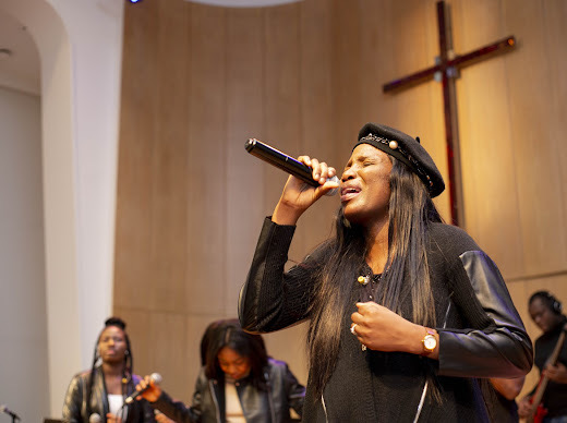 Worship leader with hands raised on stage under golden light